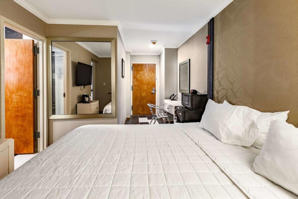 A hotel room with a king-sized bed, desk, mirror, and TV