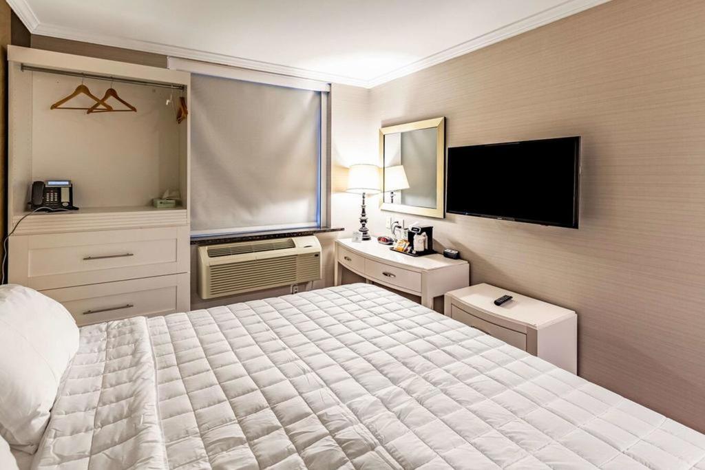 A wide view of a hotel room with a bed, desk, TV, and closet