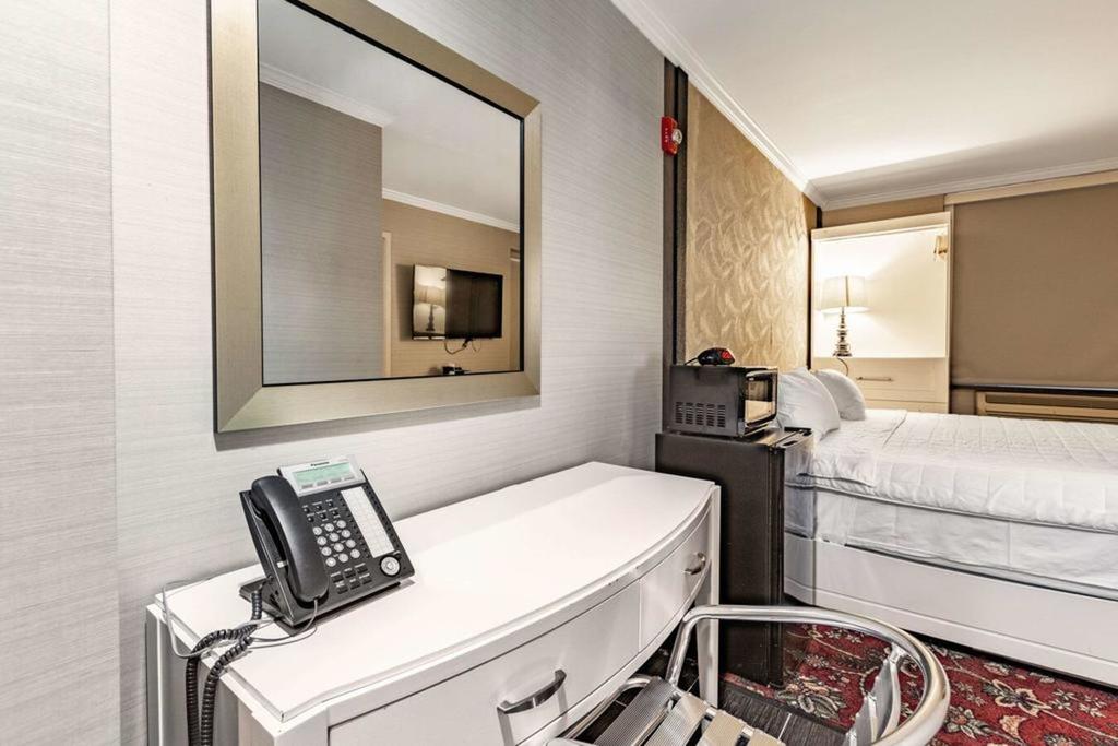 A hotel room with a bed, desk, mirror, and chair.