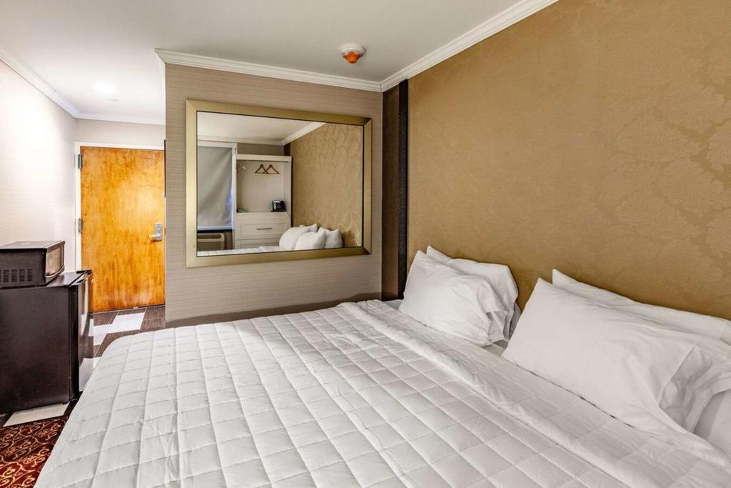A hotel room with a king-sized bed, a mirror, and a TV.